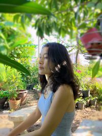 Side view of young woman looking away while sitting outdoors