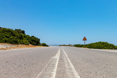 Surface level of empty road against clear blue sky