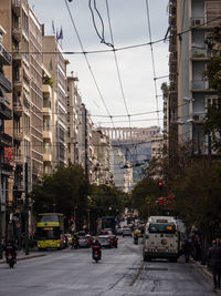 Cars on city street by buildings against sky
