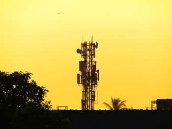 Silhouette of communications tower against sky during sunset