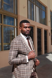 Portrait of young man standing against building