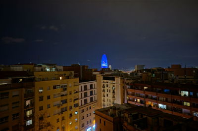 Illuminated buildings in city against sky at dusk