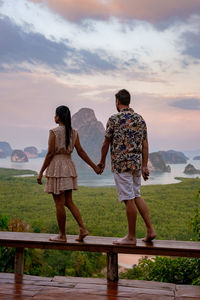 Rear view of friends standing on mountain against sky