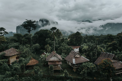 Houses by trees and buildings against sky