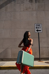 Smiling woman traveling solo in the city carrying her suitcase