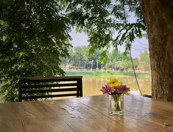 Flower vase on table against trees