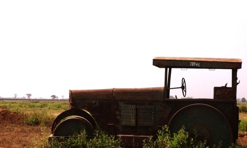 Close-up of abandoned tractor on field against clear sky