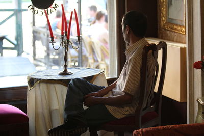 Side view of man sitting on chair in cafe