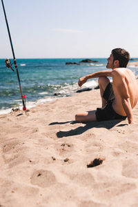 Full length of shirtless man on beach against sky