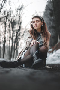 Portrait of beautiful woman sitting against trees