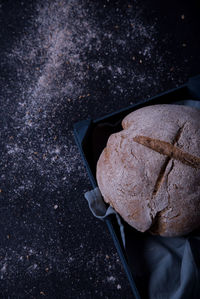 Fresh bread displayed inside a blue box with a tablecloth, on a dark background.