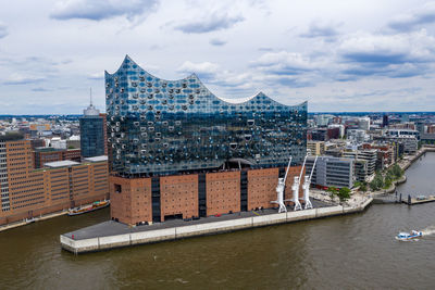 Buildings by river against sky in city