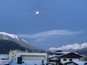 Houses and snowcapped mountains against sky