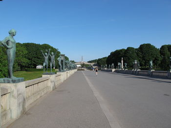 Road amidst trees against clear blue sky