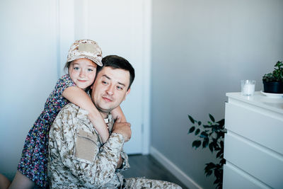 Portrait of girl embracing father in military uniform