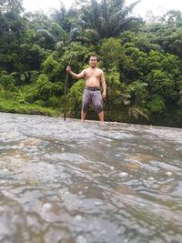 Full length of shirtless man standing in water