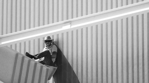 Full length of man smoking cigarette against metallic wall