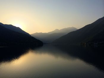 Calm lake against silhouette mountain range