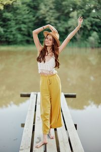 Side view of young woman standing against sky