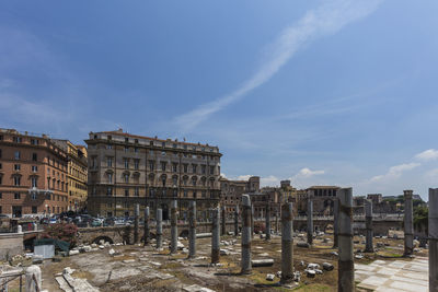Old ruins by buildings against sky