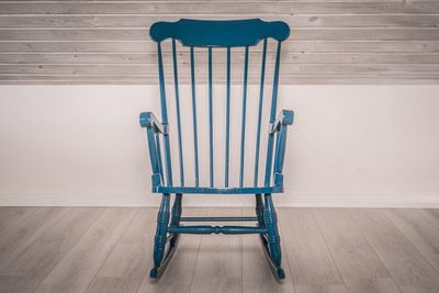 Empty chair against wall on hardwood floor at home