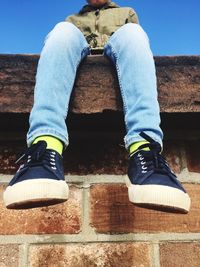 Low section of man sitting on retaining wall