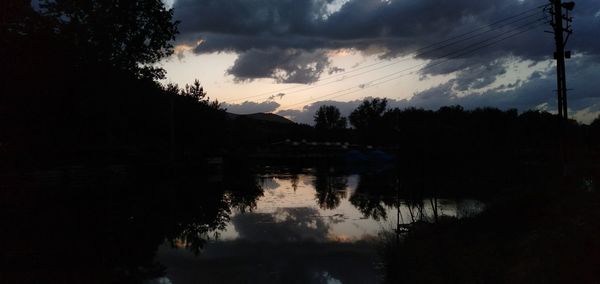 Silhouette trees by lake against sky during sunset