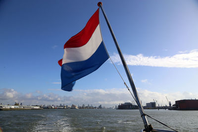 Dutch flag in city against sky