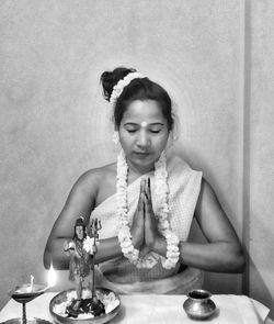 Young woman sitting on table against wall