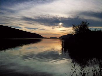 Scenic view of lake by silhouette trees against sky