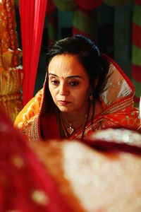 Thoughtful woman wearing sari sitting indoors