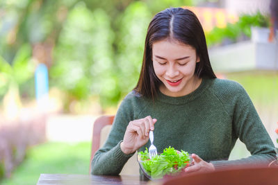 Young woman looking away while sitting on plant