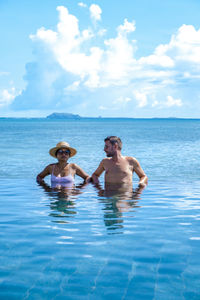 Rear view of woman swimming in sea against sky