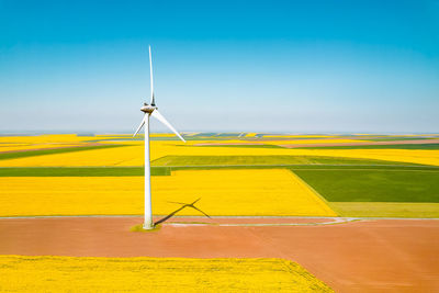 Aerial view of wind turbines farm on agricultural field in summer