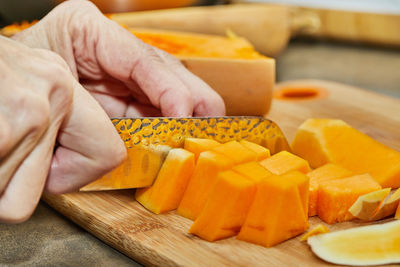 Chef cuts pumpkin in the shape of pear on wooden board in the home kitchen