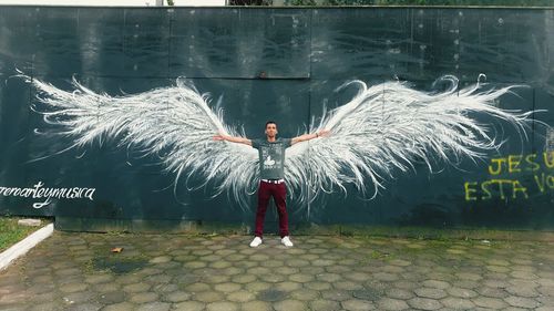 Full length of man with arms outstretched standing at night