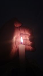 Close-up of lit candle in darkroom