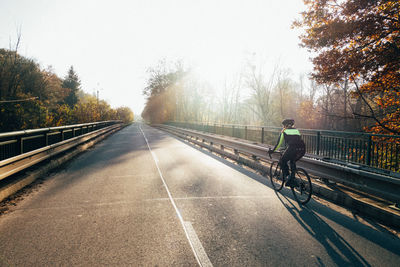 Rear view of man riding bicycle on road