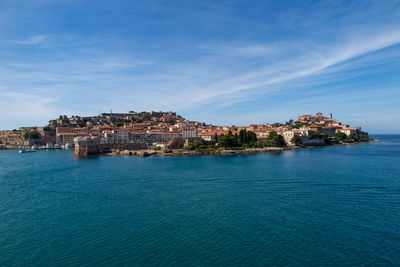 Buildings by sea against sky