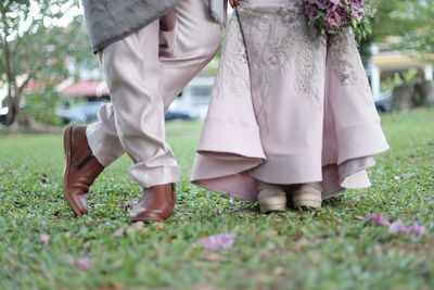 Low section of bride and groom standing on field