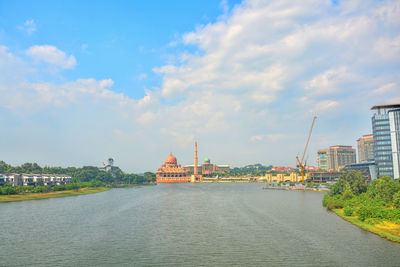 View of buildings at waterfront against cloudy sky