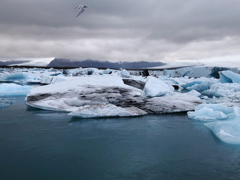 Lake by frozen ice against sky during winter