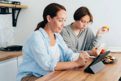 Mother and daughter eating food in kitchen