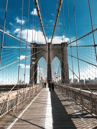 People on brooklyn bridge against sky