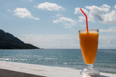 Close-up of drink on beach against sky