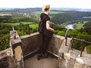 Rear view of woman standing on retaining wall