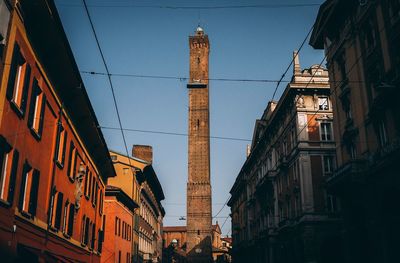 Low angle view of buildings against sky in city, torre asinelli from via rizzoli - bologna, italy