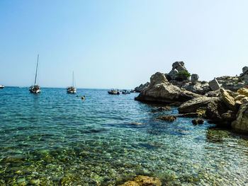 Sailboats in sea against clear sky