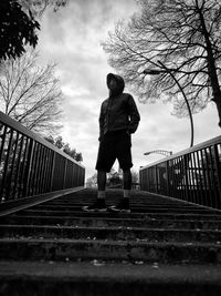 Low angle view of man standing on railing against sky