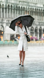 Full length of woman holding umbrella during rainy season